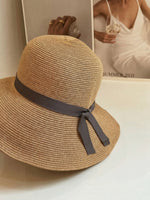 Close-up of straw cloche hat with grey ribbon bow detail