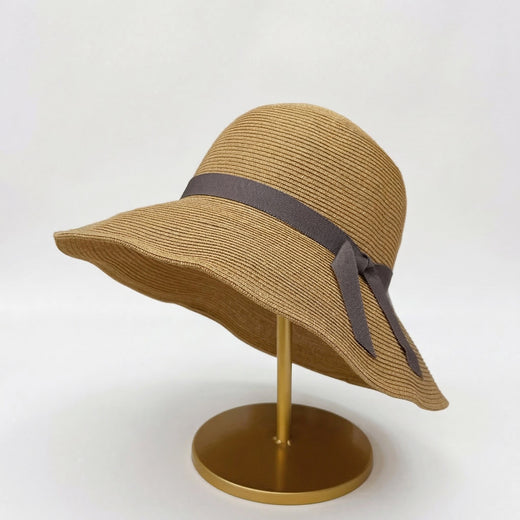 Foldable straw cloche hat with grey ribbon bow on display stand