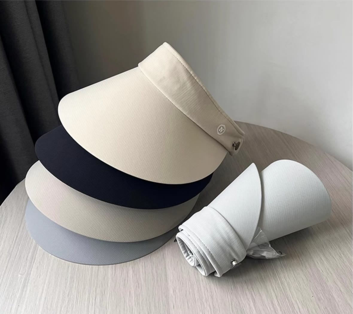 Wide brim sun visors stacked beside one visor rolled compactly for travel